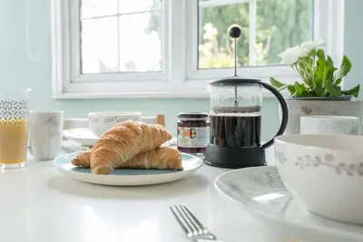 a table with a plate of croissants and a cup of coffee at Suncatch Corner, Saxmundham in Saxmundham