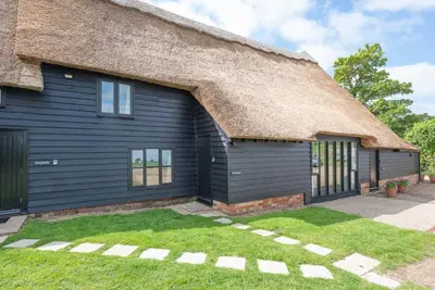 a black house with a thatched roof at Granary Cottage, Valley Farm, Snape in Saxmundham