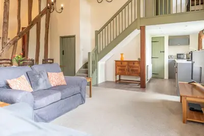 a living room with a blue couch and a kitchen at Granary Cottage, Valley Farm, Snape in Saxmundham
