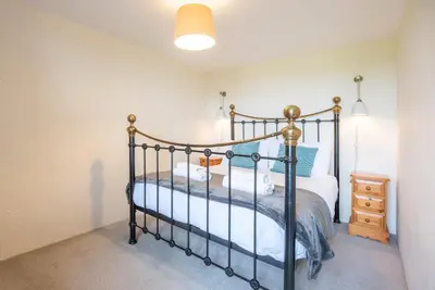 a bedroom with a bed and a night stand at Granary Cottage, Valley Farm, Snape in Saxmundham