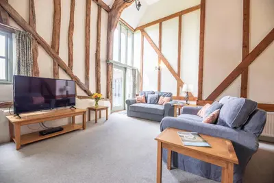 a living room with two couches and a flat screen tv at Granary Cottage, Valley Farm, Snape in Saxmundham