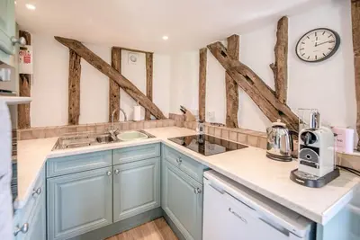 a kitchen with blue cabinets and a clock on the wall at The Hayloft, Valley Farm, Snape in Saxmundham