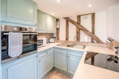 a kitchen with blue cabinets and white appliances at The Hayloft, Valley Farm, Snape in Saxmundham