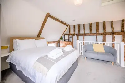 a bedroom with a bed and a blue chair at The Hayloft, Valley Farm, Snape in Saxmundham