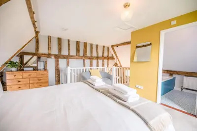 a bedroom with a large bed and a yellow wall at The Hayloft, Valley Farm, Snape in Saxmundham