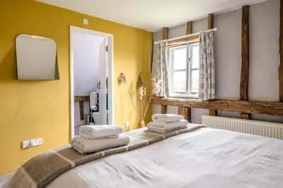 a bedroom with yellow walls and a bed with towels at The Hayloft, Valley Farm, Snape in Saxmundham