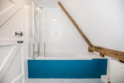 a bathroom with a shower and a blue tub at The Hayloft, Valley Farm, Snape in Saxmundham