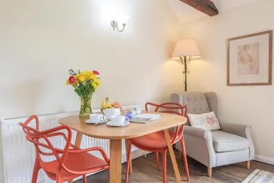 a table and chairs with a vase of flowers on it at The Stables, Valley Farm, Snape in Saxmundham