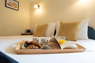 a tray with a plate of food and a book on a bed at The Stables, Valley Farm, Snape in Saxmundham