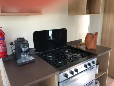 a kitchen with a stove and a coffee maker on a counter at Tref y Clawdd in Felixstowe