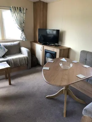 a living room with a table and a tv at Tref y Clawdd in Felixstowe
