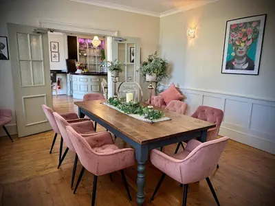 a dining room with a table and pink chairs at Slepe Hall Hotel in St Ives