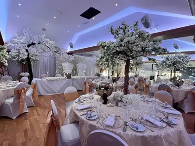 a banquet hall with white tables and chairs and trees at Slepe Hall Hotel in St Ives