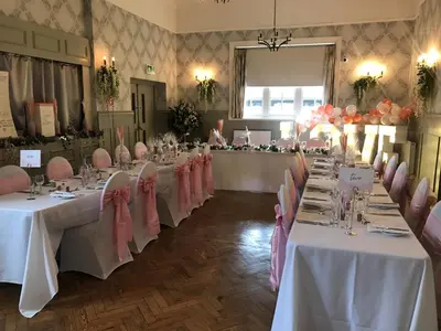 a room with tables with pink and white tablecloths at Slepe Hall Hotel in St Ives