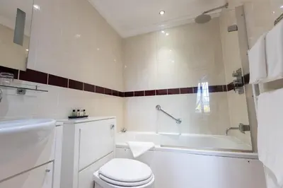 a bathroom with a toilet and a tub and a sink at Slepe Hall Hotel in St Ives