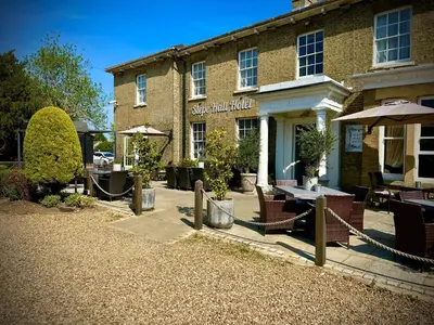 a brick building with chairs and a table and umbrella at Slepe Hall Hotel in St Ives