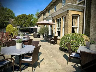 a patio with tables and chairs and an umbrella at Slepe Hall Hotel in St Ives