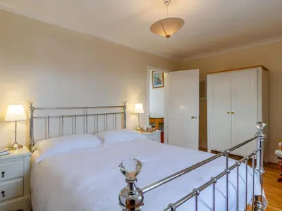 a bedroom with a large bed with white sheets at Mayflower Cottage in Harwich