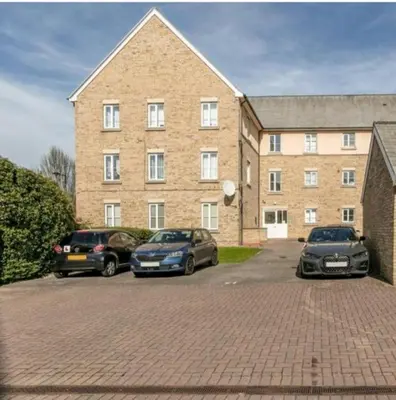 three cars parked in front of a large brick building at Elegant 2 BR Apartment in Historic Cambridge in Papworth Everard