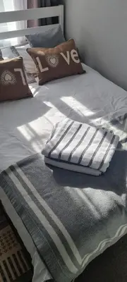 a bed with a blue and white blanket on it at Elegant 2 BR Apartment in Historic Cambridge in Papworth Everard