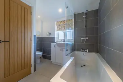 a bathroom with a tub and a sink and a toilet at Yew Tree Cottage in Westleton