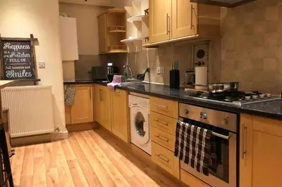 a kitchen with wooden cabinets and a washer and dryer at Quirky 3 bedroom property in Wymondham