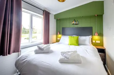 a bedroom with a large white bed with green walls at Sea Cloud in Aldeburgh