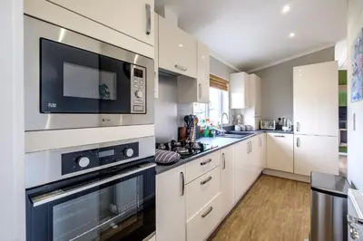 a large kitchen with white cabinets and a microwave at Sea Cloud in Aldeburgh