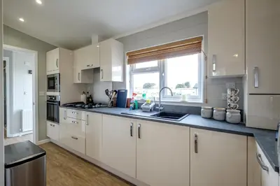 a kitchen with white cabinets and a sink and a window at Sea Cloud in Aldeburgh