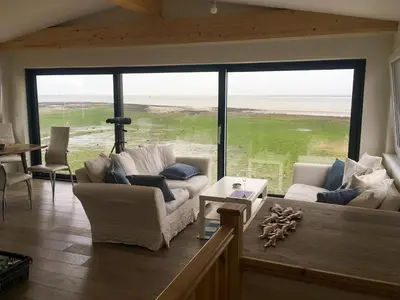 a living room with two couches and a large window at Curlew in Brightlingsea