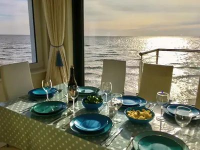 a table with plates and wine glasses and a view of the ocean at Curlew in Brightlingsea