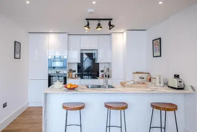 a kitchen with a counter and two stools at One The Old School, Leiston in Leiston