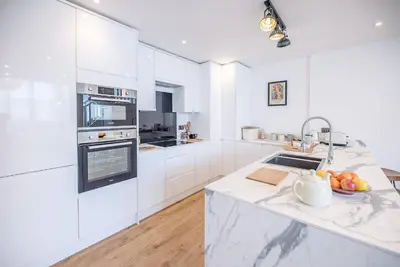 a white kitchen with white cabinets and a sink at One The Old School, Leiston in Leiston
