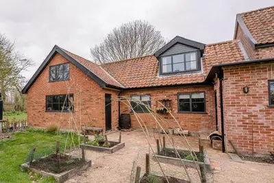 a brick house with two potted plants in front of it at Red House Loft, East Green in Saxmundham