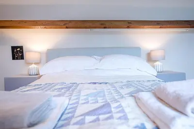 a bedroom with a bed with two lamps on either side at Red House Loft, East Green in Saxmundham