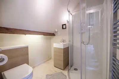a bathroom with a shower and a toilet and a sink at Red House Loft, East Green in Saxmundham