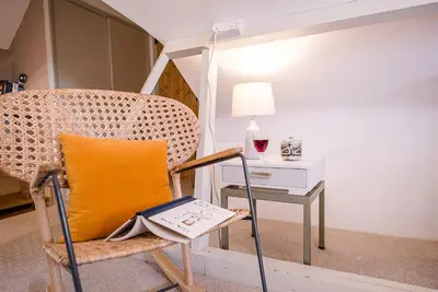 a chair with a yellow pillow sitting next to a table at Red House Loft, East Green in Saxmundham