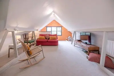 a living room with a red couch and a table at Red House Loft, East Green in Saxmundham