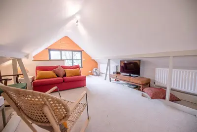 a living room with a red couch and a tv at Red House Loft, East Green in Saxmundham