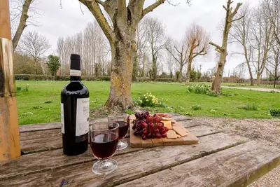 a bottle of wine and wine glasses on a wooden table at Red House Loft, East Green in Saxmundham