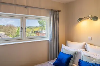 a bedroom with a window and a bed with blue pillows at Immaculate luxury retreat in pretty village with great pubs - Box Valley Cottage in Stoke by Nayland
