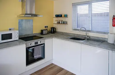 a kitchen with white cabinets and a sink and a microwave at Walking distance to hospital and town with free off-road parking in Bury Saint Edmunds