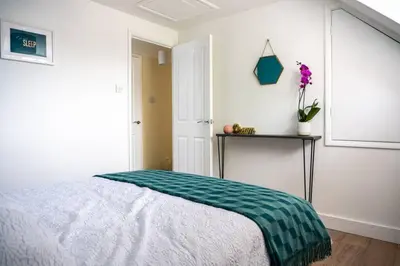 a bedroom with a bed with a green and white blanket at Walking distance to hospital and town with free off-road parking in Bury Saint Edmunds