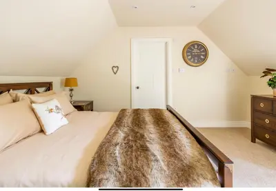 a bedroom with a large bed and a clock on the wall at The Cartlodge in Wickham Bishops