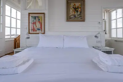 a large white bed in a white bedroom with two lamps at The Boathouse in Felixstowe Ferry - Stunning Waterfront Property in Felixstowe