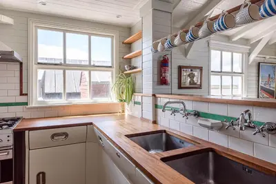a kitchen with a sink and two windows at The Boathouse in Felixstowe Ferry - Stunning Waterfront Property in Felixstowe