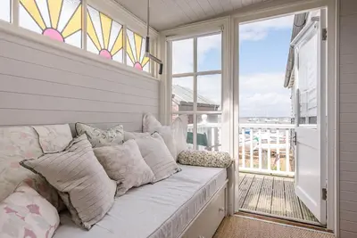 a white couch sitting on a balcony with a window at The Boathouse in Felixstowe Ferry - Stunning Waterfront Property in Felixstowe