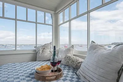 a room with a bed with a glass of wine and pillows at The Boathouse in Felixstowe Ferry - Stunning Waterfront Property in Felixstowe