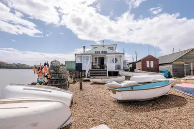 a group of boats on the shore of a house at The Boathouse in Felixstowe Ferry - Stunning Waterfront Property in Felixstowe