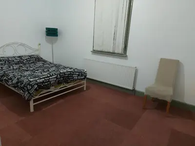 a bedroom with a bed and a chair and a window at Queen Suite in Ipswich